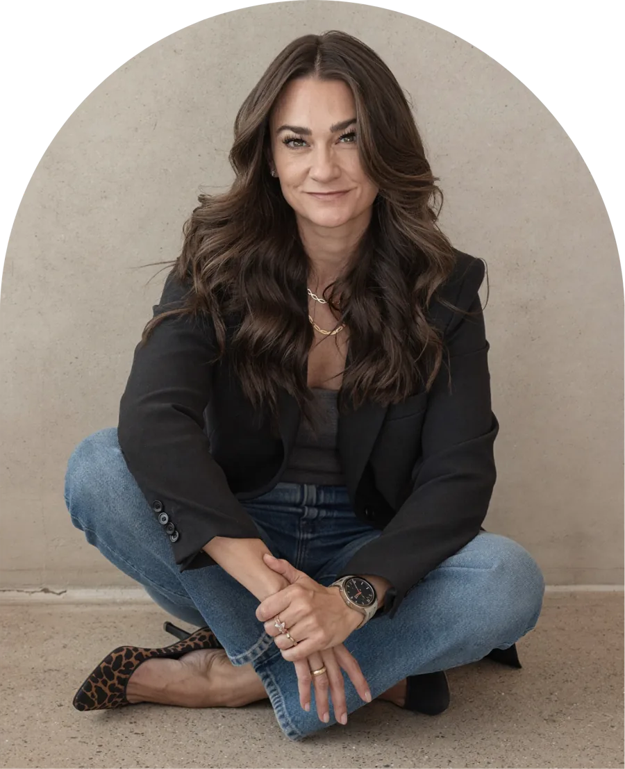 Kasey Ingram, sitting on the floor in a black blazer and jeans