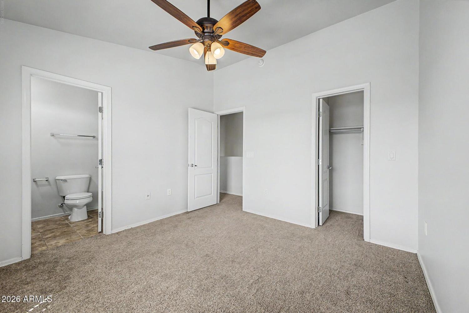 Primary bedroom with ceiling fan and ensuite bath