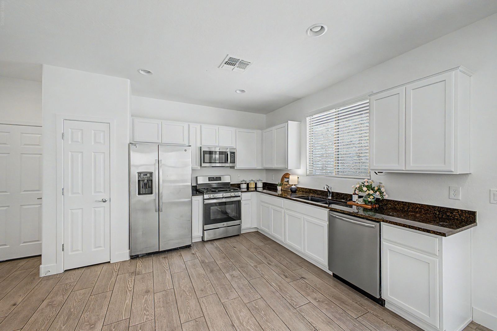 White kitchen with granite countertops and stainless appliances