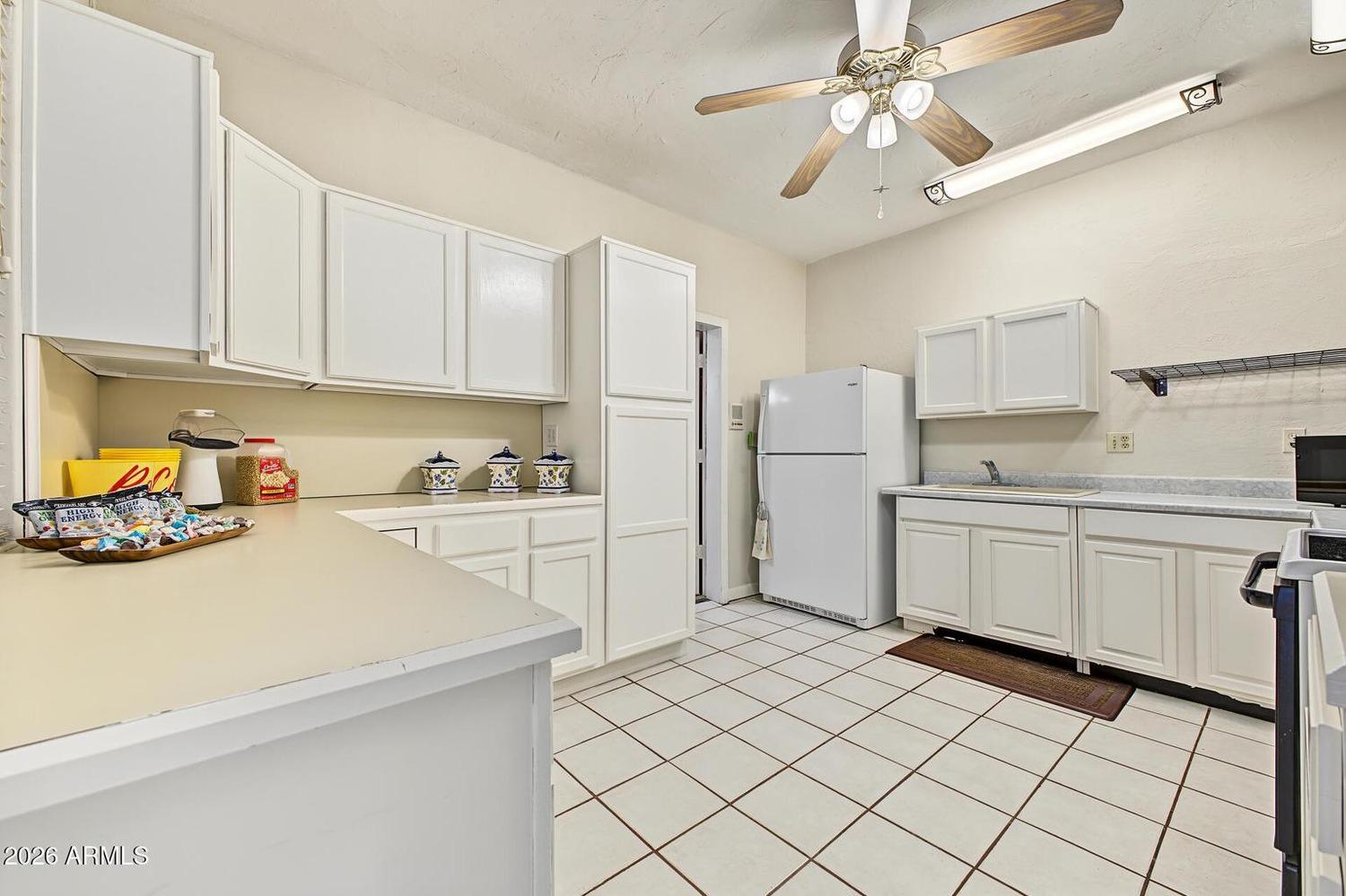 Second kitchen with white cabinets and refrigerator