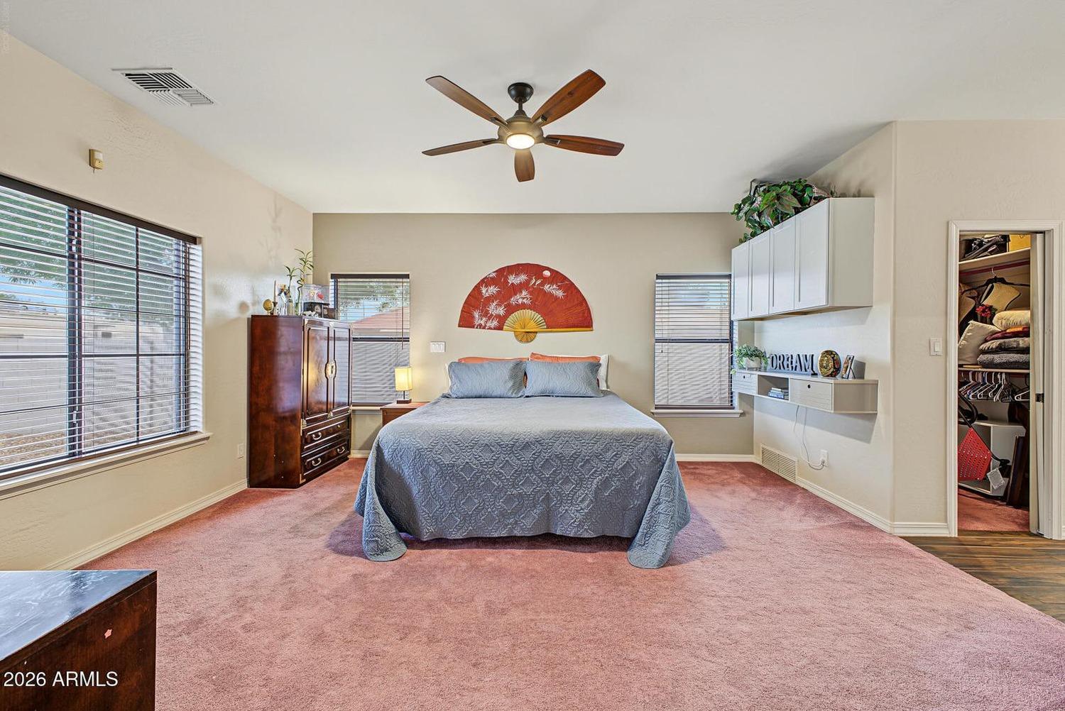 Primary bedroom with ceiling fan and windows