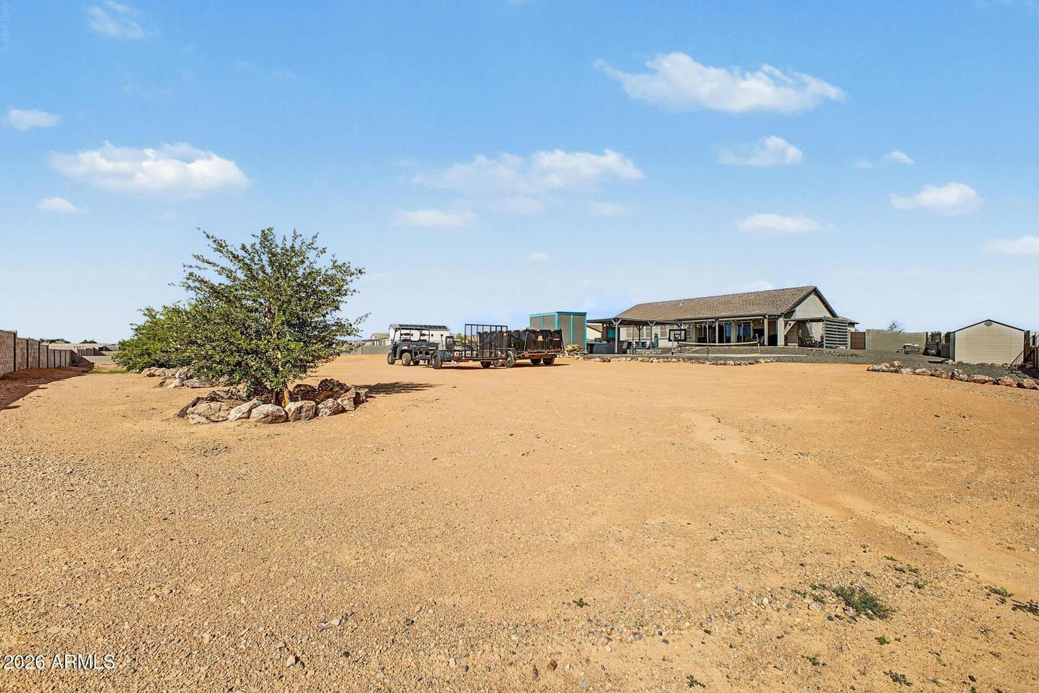 Wide view of the open dirt portion of the lot with the house in the distance