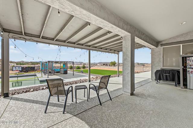 Covered patio with string lights looking toward the pool and lawn