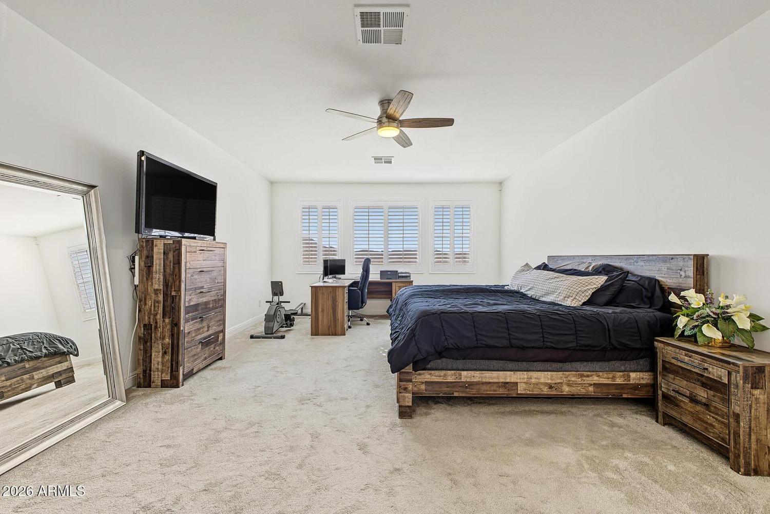 Primary bedroom with carpet, ceiling fan and plantation shutters